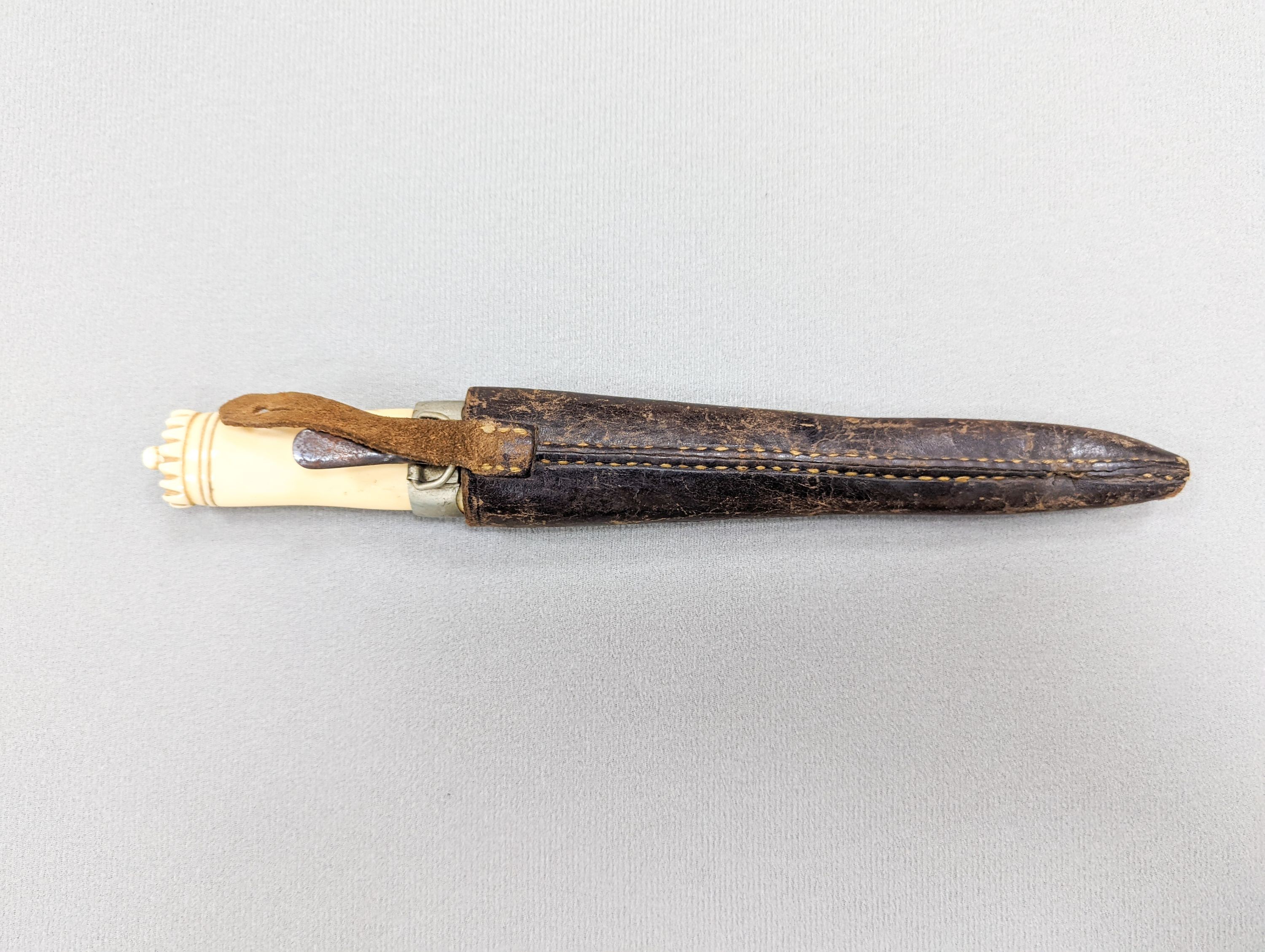 An antique Norwegian marine ivory hunting knife, with carved and pierced scabbard and leather outer sheath, the blade signed Blikstad, Trondhjem, scabbard damaged, overall 26.5cm.